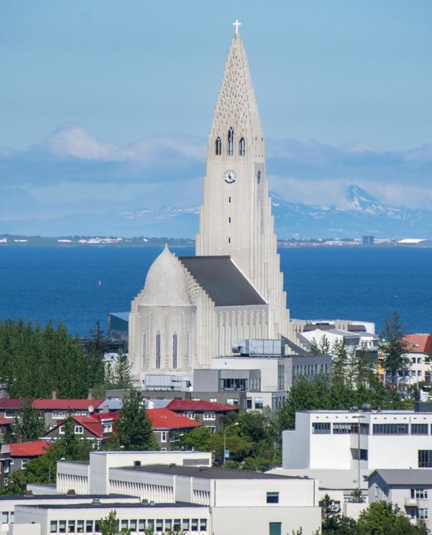 一个冰岛教堂的塔在大海和山的背景